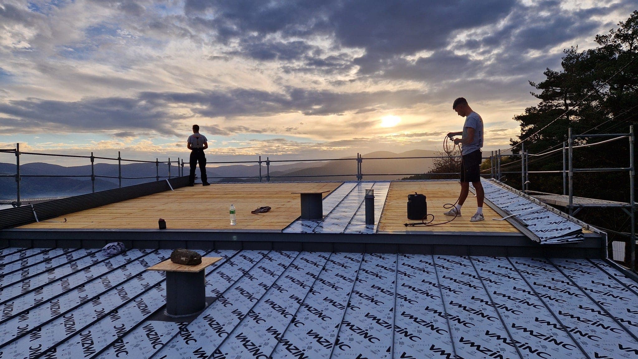 Deux couvreurs de Reck Couverture sur une toiture en zinc au coucher du soleil, au Hohrodberg